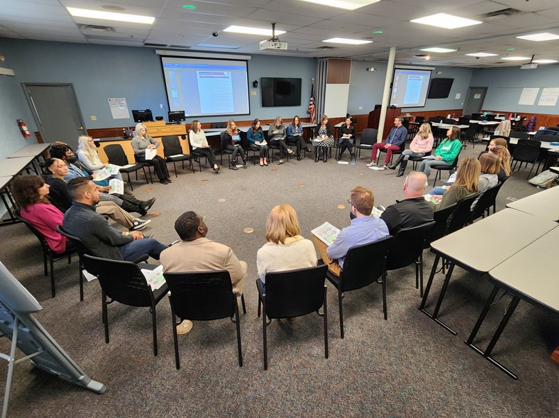 24 people sitting in chairs in a big circle
