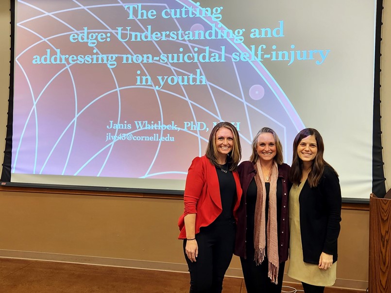 3 ladies posing in front of a projector slide