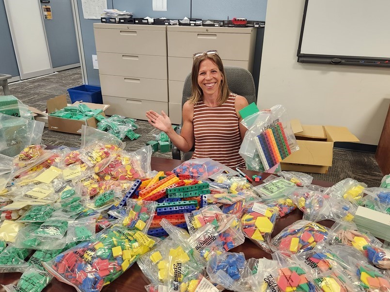 LADY SITTING AT TABLE SORTING MATH MANIPULATIVES
